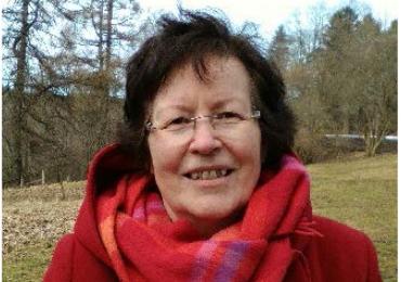 Official Statistics: Asta Manninen with red jacket and scarf standing in a meadow